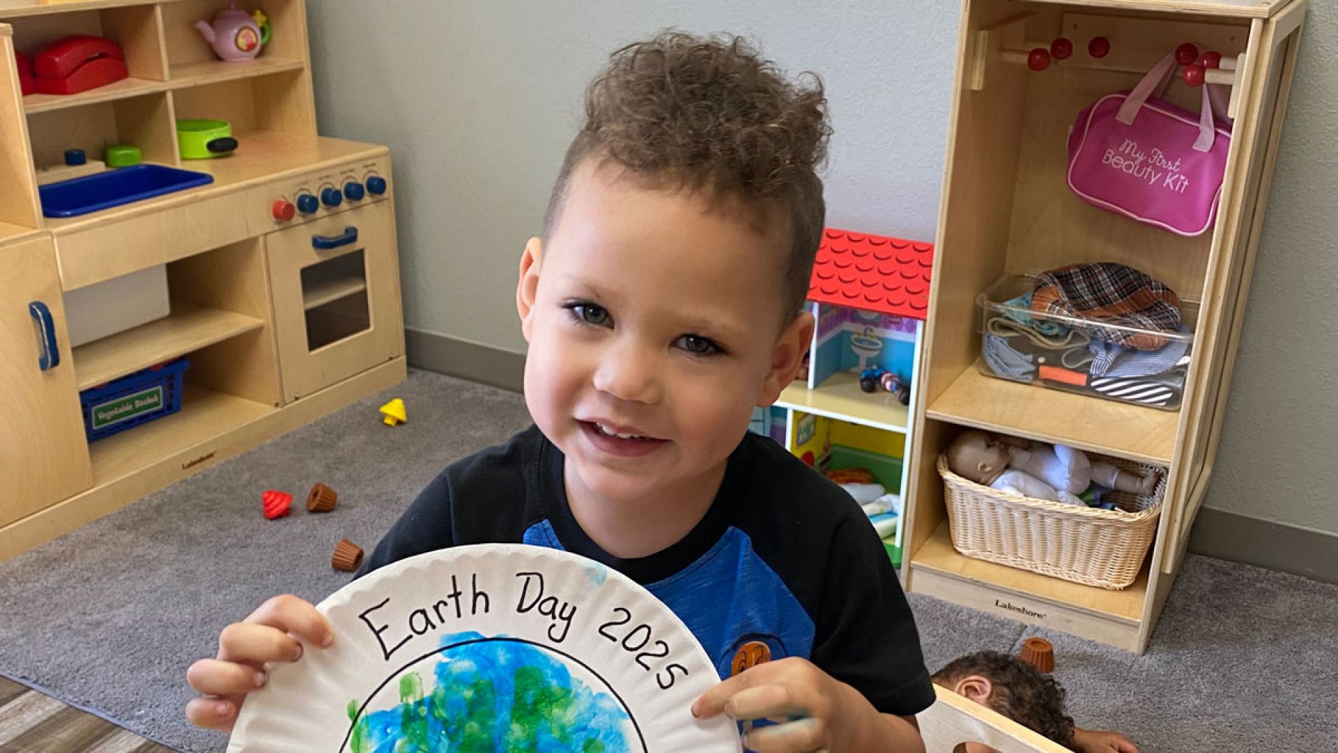 child holding up earth day craft